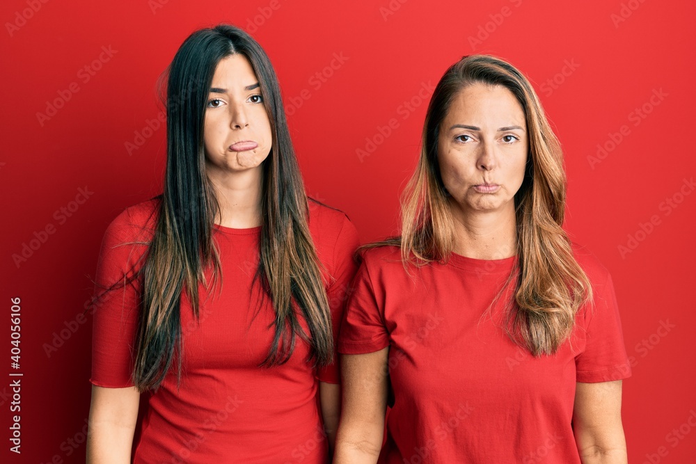 Hispanic family of mother and daughter wearing casual clothes over red background depressed and worry for distress, crying angry and afraid. sad expression. Hispanic family of mother and daughter wearing casual clothes over red background depressed and worry for distress, crying angry and afraid. sad expression.