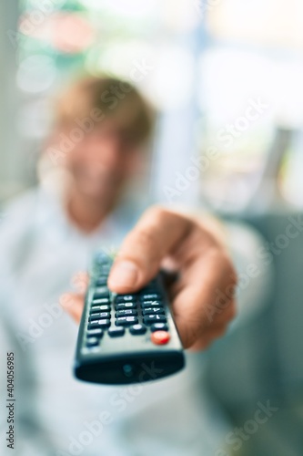 Close up of middle age handsome caucasian man using tv control