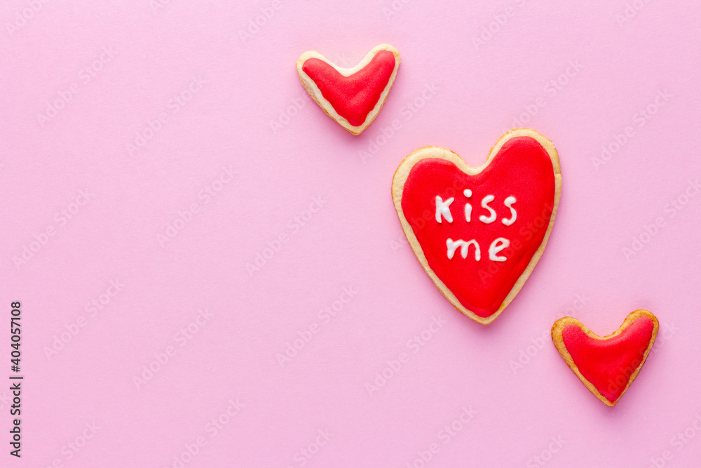 Heart shaped cookies with red sugar icing and word love for St Valentine day on pink background