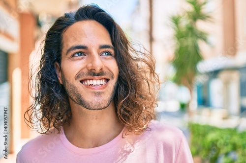 Young hispanic man smiling happy looking to the side at city.