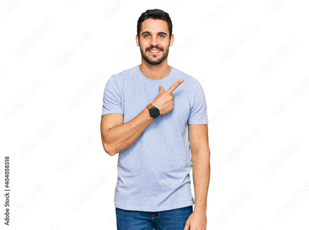Young hispanic man wearing casual clothes cheerful with a smile on face pointing with hand and finger up to the side with happy and natural expression Young hispanic man wearing casual clothes cheerful with a smile on face pointing with hand and finger up to the side with happy and natural expression