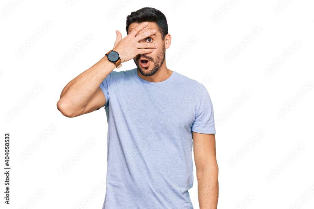 Young hispanic man wearing casual clothes peeking in shock covering face and eyes with hand, looking through fingers with embarrassed expression. Young hispanic man wearing casual clothes peeking in shock covering face and eyes with hand, looking through fingers with embarrassed expression.