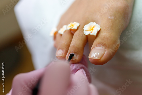 applying transparent varnish during pedicure