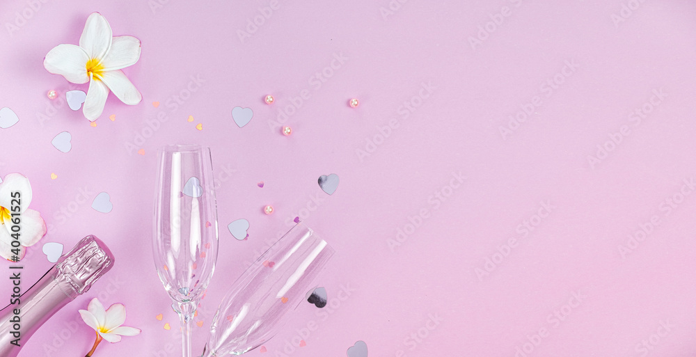 Two empty champagne glasses and bottle of champagne with white frangipani flowers and small heart decoration on pink background, copy space, Valentines background Two empty champagne glasses and bottle of champagne with white frangipani flowers and small heart decoration on pink background, copy space, Valentines background