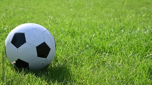 Football ball rolling on green grass field