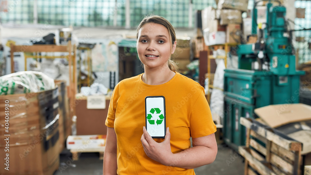Obraz premium Young girl holding smartphone with recycling sign