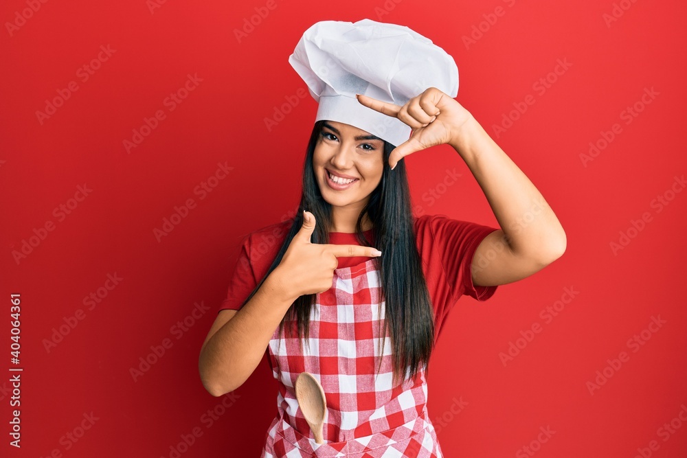 Young beautiful hispanic girl wearing baker uniform and cook hat smiling making frame with hands and fingers with happy face. creativity and photography concept. Young beautiful hispanic girl wearing baker uniform and cook hat smiling making frame with hands and fingers with happy face. creativity and photography concept.