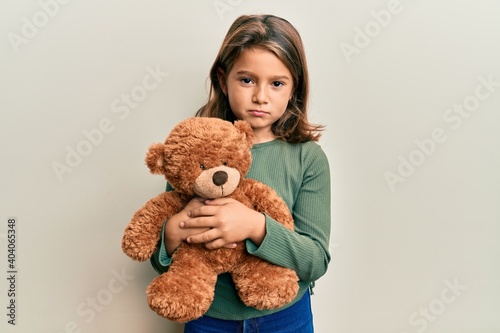 Little beautiful girl hugging teddy bear depressed and worry for distress, crying angry and afraid. sad expression.
