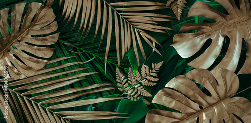 Creative nature background. Gold and green tropical Monstera and palm leaves. Minimal summer abstract jungle or forest pattern.
