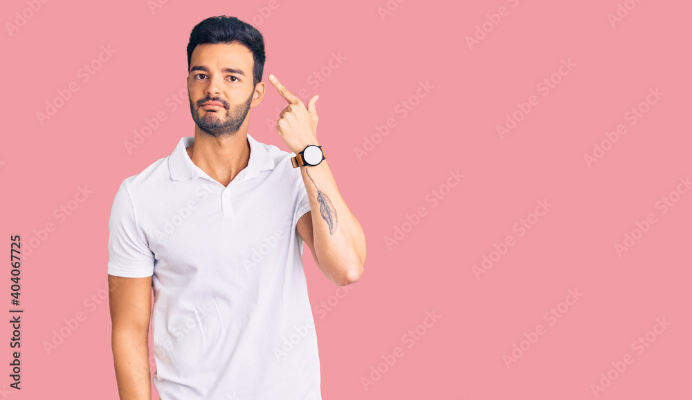 Young handsome hispanic man wearing casual clothes shooting and killing oneself pointing hand and fingers to head like gun, suicide gesture. Young handsome hispanic man wearing casual clothes shooting and killing oneself pointing hand and fingers to head like gun, suicide gesture.