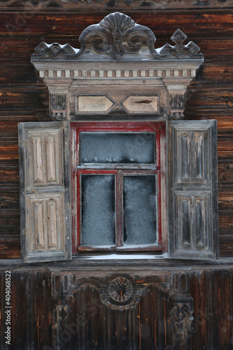 Ornamental window with carved frame of ancient rural wooden house (