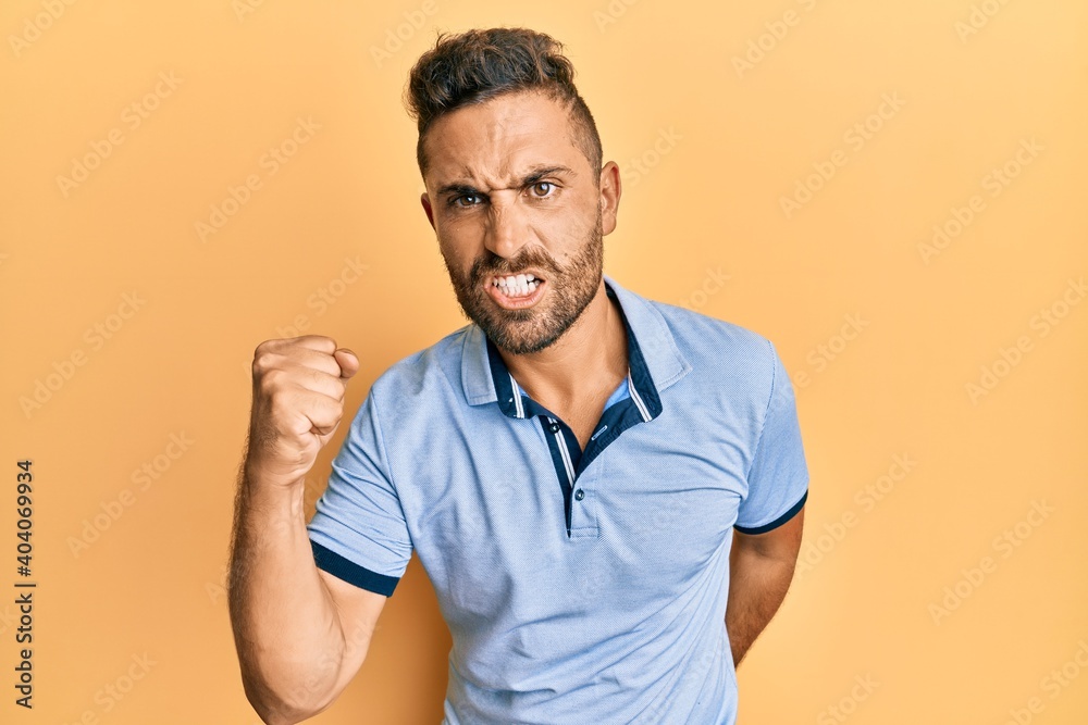 Handsome man with beard wearing casual clothes angry and mad raising fist frustrated and furious while shouting with anger. rage and aggressive concept. Handsome man with beard wearing casual clothes angry and mad raising fist frustrated and furious while shouting with anger. rage and aggressive concept.