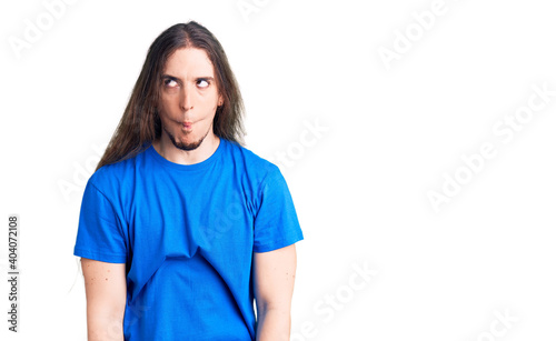 Young adult man with long hair wearing swimwear making fish face with lips, crazy and comical gesture. funny expression.