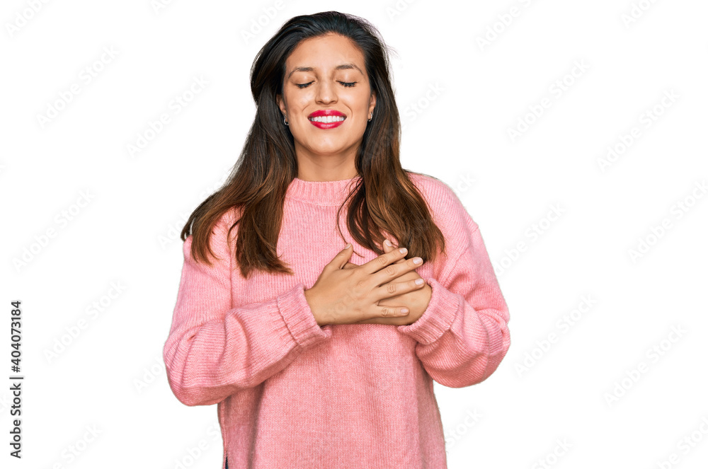 Beautiful hispanic woman wearing casual winter sweater smiling with hands on chest with closed eyes and grateful gesture on face. health concept. Beautiful hispanic woman wearing casual winter sweater smiling with hands on chest with closed eyes and grateful gesture on face. health concept.
