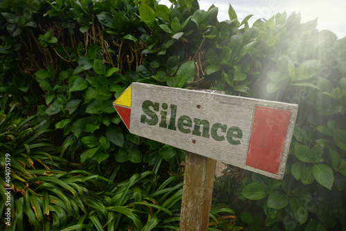 vintage old wooden signboard with text silence near the green plants.