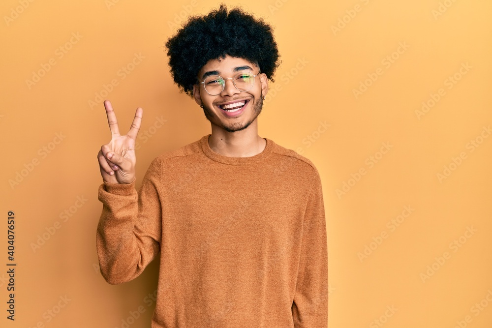 Young african american man with afro hair wearing casual winter sweater showing and pointing up with fingers number two while smiling confident and happy. Young african american man with afro hair wearing casual winter sweater showing and pointing up with fingers number two while smiling confident and happy.