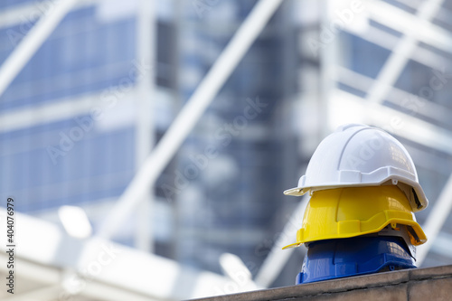 Close up Blue, yellow and white hard safety helmet hats for safety project of workman as engineering or project worker place on concrete floor city outdoor.