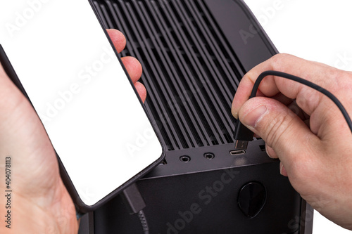 Close up view of man hands connecting usb cable mobile phone with mockup image blank screens to computer. 