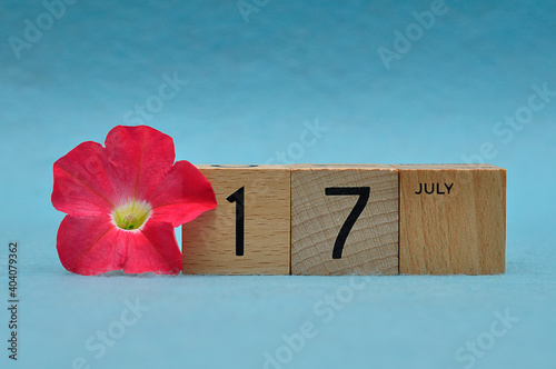 17 July on wooden blocks with a Petunia on a blue background