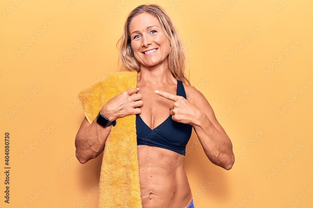 Middle age caucasian blonde woman wearing bikini and towel smiling happy pointing with hand and finger Middle age caucasian blonde woman wearing bikini and towel smiling happy pointing with hand and finger