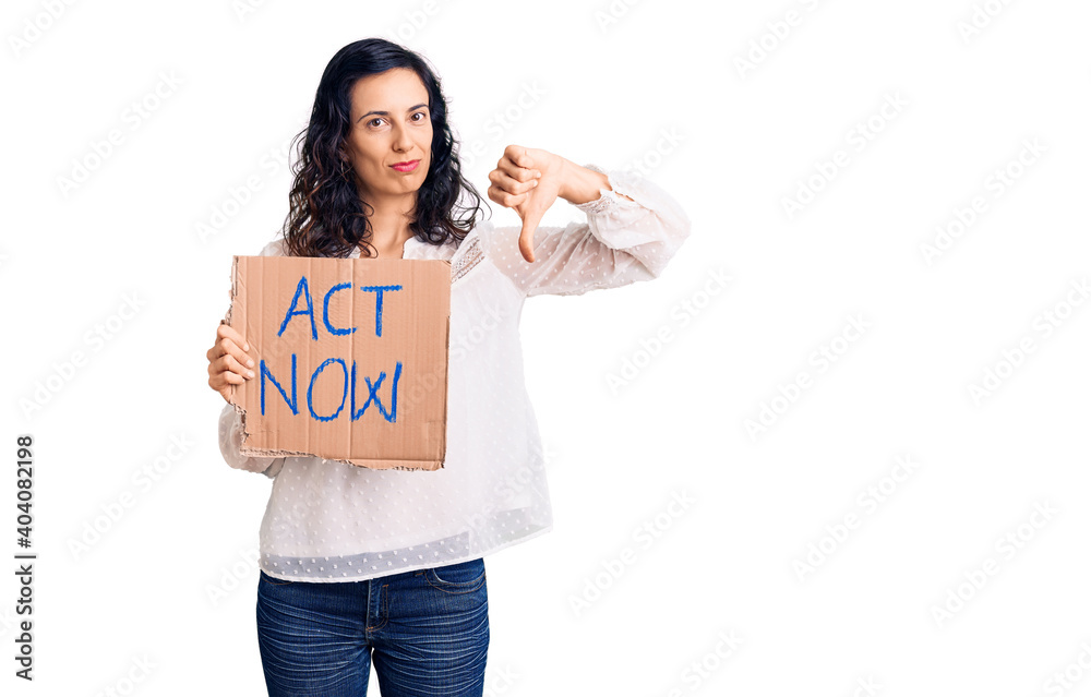 Young beautiful hispanic woman holding act now banner with angry face, negative sign showing dislike with thumbs down, rejection concept Young beautiful hispanic woman holding act now banner with angry face, negative sign showing dislike with thumbs down, rejection concept