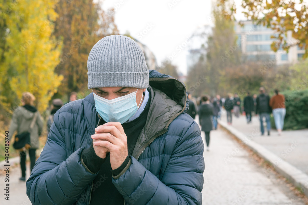 Incorrect way of sneezing or coughing into a protective medical face mask, outdoors. Prevent the spread of the Coronavirus Disease 2019 (COVID-19) Incorrect way of sneezing or coughing into a protective medical face mask, outdoors. Prevent the spread of the Coronavirus Disease 2019 (COVID-19)