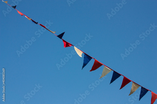 A sprawling garland of triangular colored flags against a blue sky