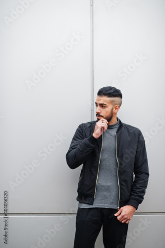 Portrait of stylish arab beard man wear grey turtleneck and black jaket. Arabian model guy against steel wall.