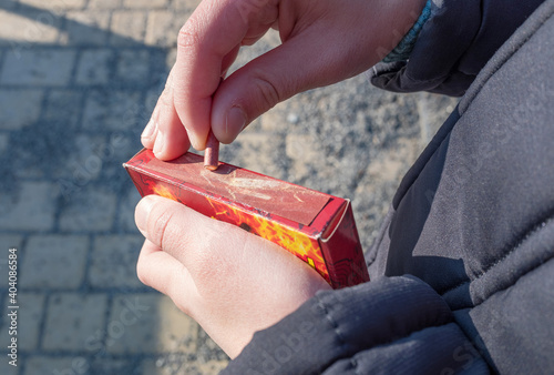 Young caucasian boy lighting a small firecracker or petard in his hand