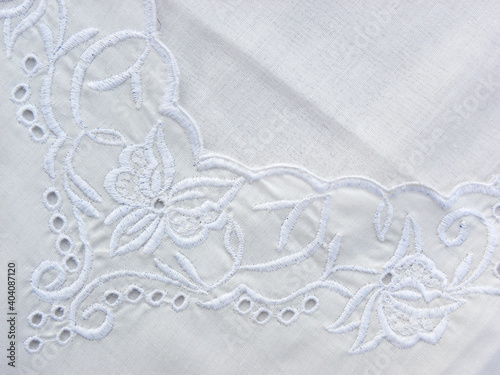 Embroidered pattern with white threads on white cotton fabric, decorated fabric