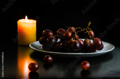 A bunch of red grapes and a candle.