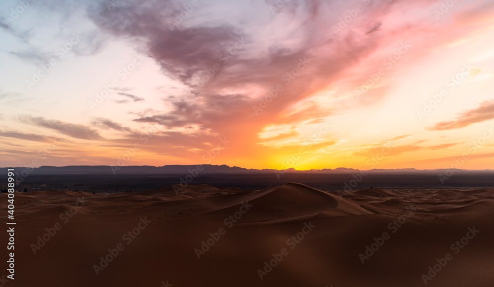 (Selective focus) Stunning view of some sand dunes illuminated at sunset. Merzouga, Morocco. Natural background with copy space.
