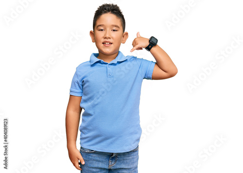 Little boy hispanic kid wearing casual clothes smiling doing phone gesture with hand and fingers like talking on the telephone. communicating concepts.