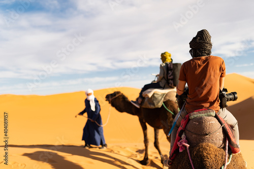 (Selective focus) Stunning view of two people riding camels on the sand dunes in Merzouga, Morocco. Merzouga is a small village in southeastern Morocco. © Travel Wild
