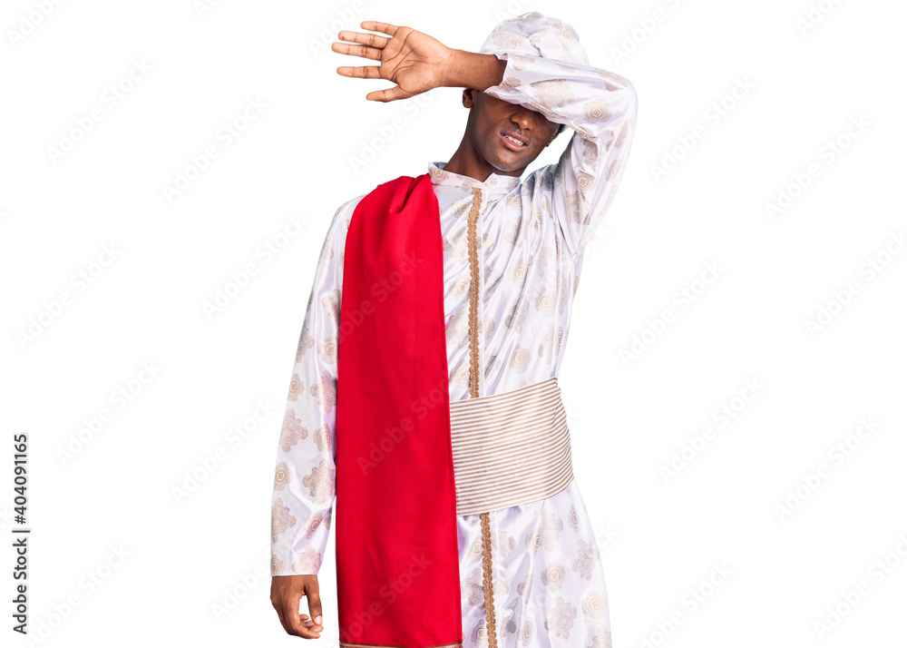 African handsome man wearing tradition sherwani saree clothes covering eyes with arm, looking serious and sad. sightless, hiding and rejection concept