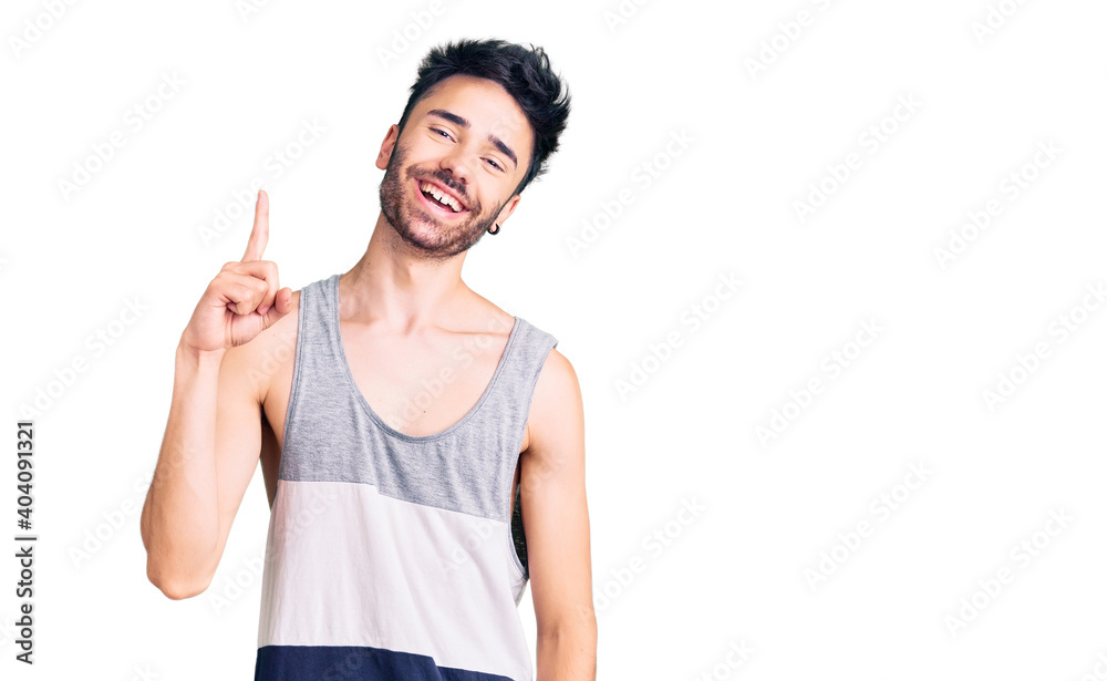 Young hispanic man wearing casual clothes showing and pointing up with finger number one while smiling confident and happy. Young hispanic man wearing casual clothes showing and pointing up with finger number one while smiling confident and happy.