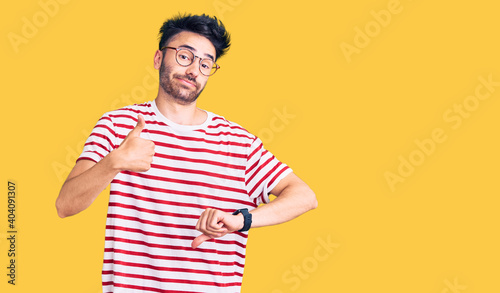 Young hispanic man wearing casual clothes doing thumbs up and down, disagreement and agreement expression. crazy conflict