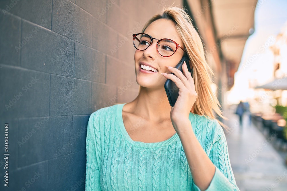Fototapeta premium Young blonde woman smiling happy talking on the smartphone at the city.