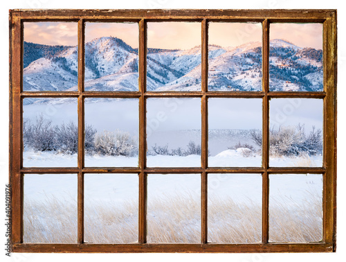 scenery of a mountain lake and valley covered by fog at winter sunrise as seen from a sash window of vintage cabin