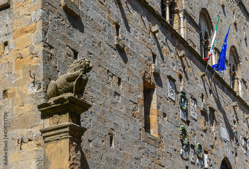 Detail of the façade of the Palazzo dei Priori (13th century), town hall of Volterra, with the Marzocco, an heraldic lion symbol of Florence, on a column, Pisa, Tuscany, Italy photo