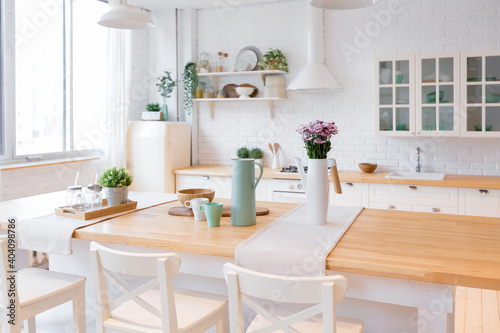 Stylish kitchen in light colors in a trendy modern duplex apartment with large high windows.