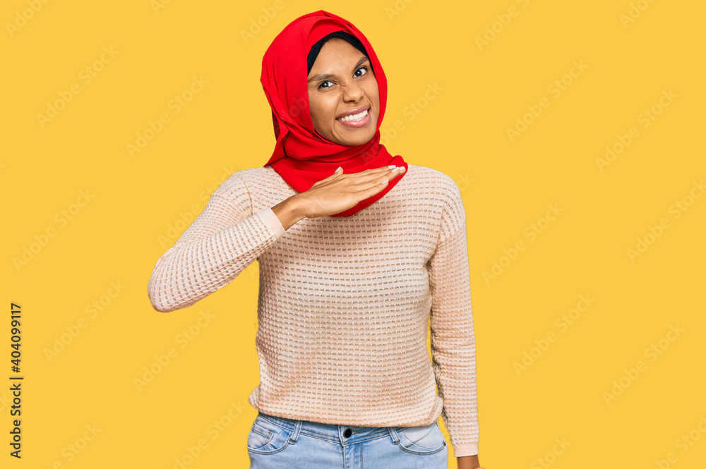 Young african american woman wearing traditional islamic hijab scarf cutting throat with hand as knife, threaten aggression with furious violence Young african american woman wearing traditional islamic hijab scarf cutting throat with hand as knife, threaten aggression with furious violence