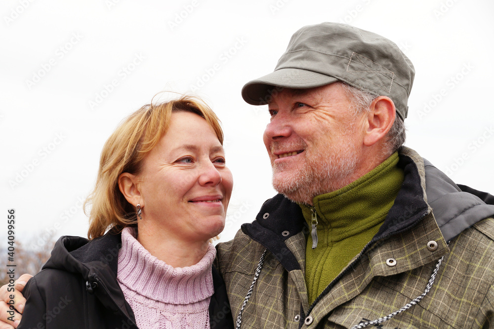 Smiling middle-aged man and woman standing hugging in nature Smiling middle-aged man and woman standing hugging in nature