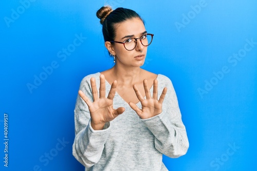 Young hispanic woman wearing casual clothes moving away hands palms showing refusal and denial with afraid and disgusting expression. stop and forbidden.