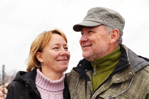 Smiling middle-aged man and woman standing hugging in nature