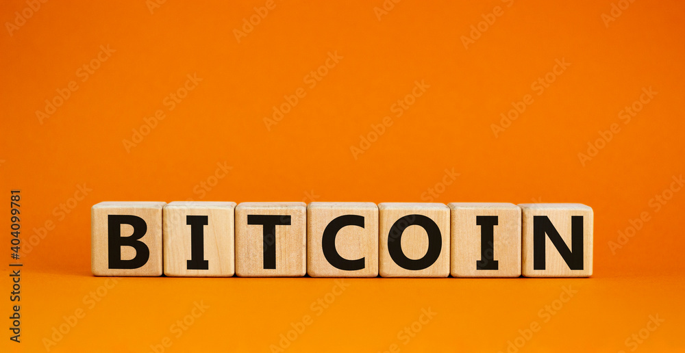 Bitcoin symbol. Wooden cubes with the word 'bitcoin'. Beautiful orange background, copy space. Business and bitcoin concept.