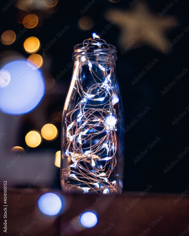 Botella con luces led dentro con fondo de árbol de navidad 