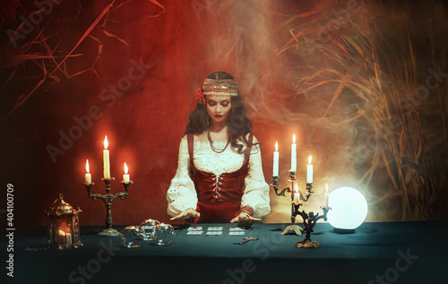 Cuadro en lienzo Fantasy girl in image of gypsy witch sits at table in dark gothic room