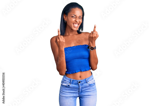 Young african american woman wearing casual summer clothes showing middle finger doing fuck you bad expression  provocation and rude attitude. screaming excited