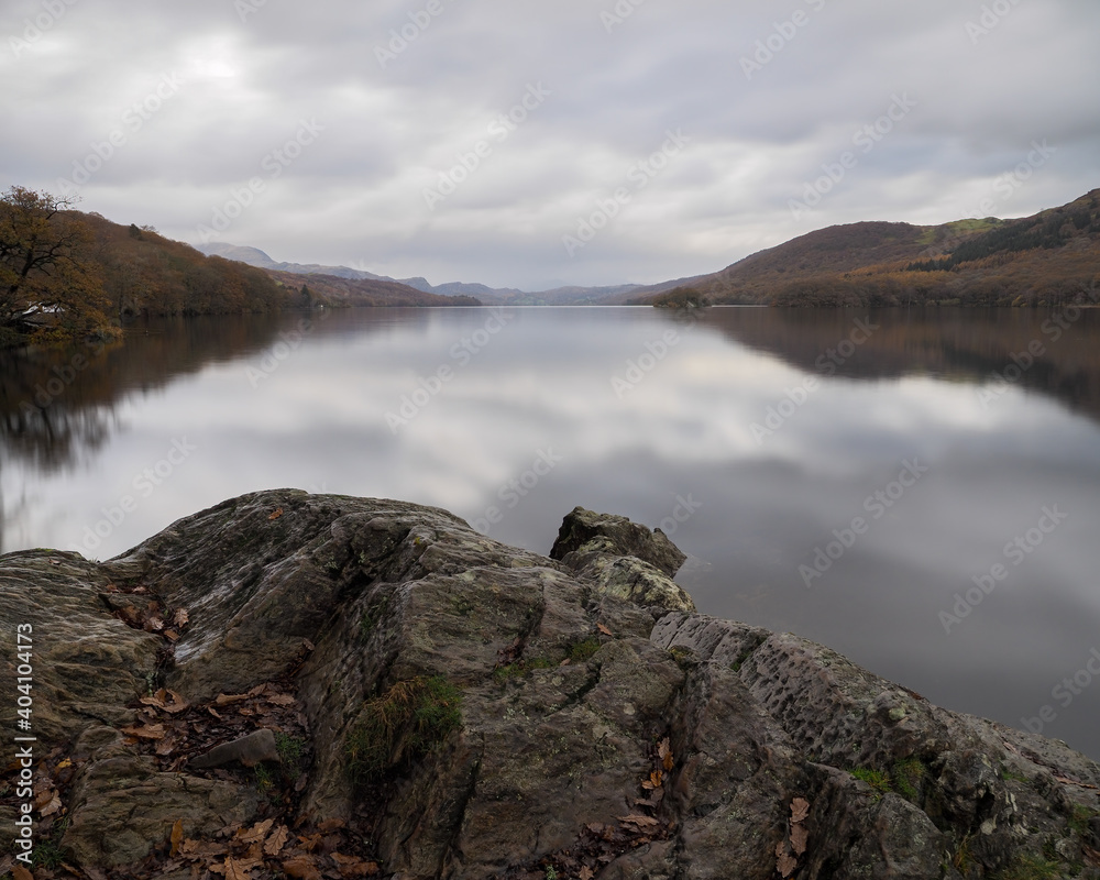 View over the calmness of Coniston Water with the fells in the background and clouds reflected in the water, Lake District, UK